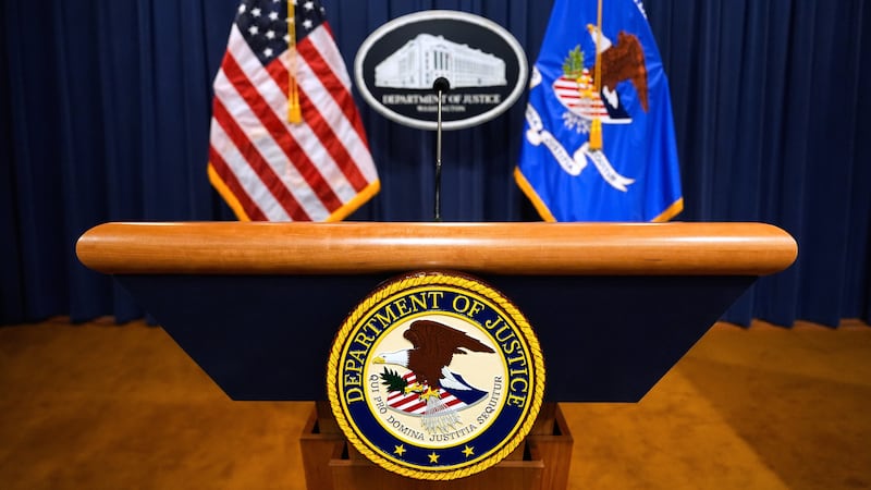 FILE - The U.S. Department of Justice logo is seen on a podium before a press conference, May...