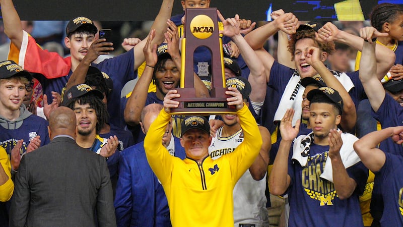 Michigan head coach Dusty May hold up the trophy as he celebrates after defeating UConn in the...